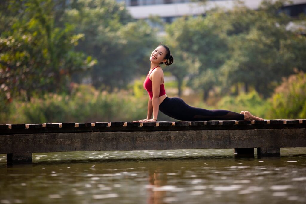 A woman enjoys a yoga pose on a bridge, showcasing flexibility and relaxation in a natural setting.